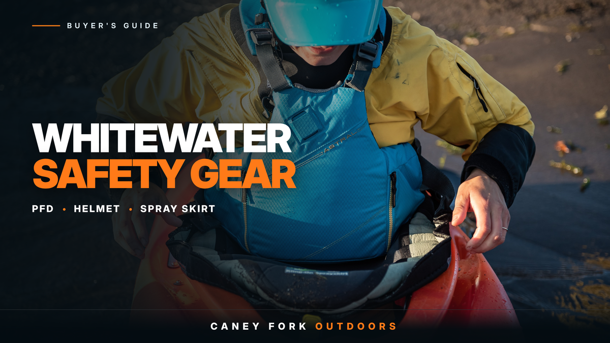 Whitewater paddler in a life jacket and helmet pulling a spray skirt onto the cockpit rim